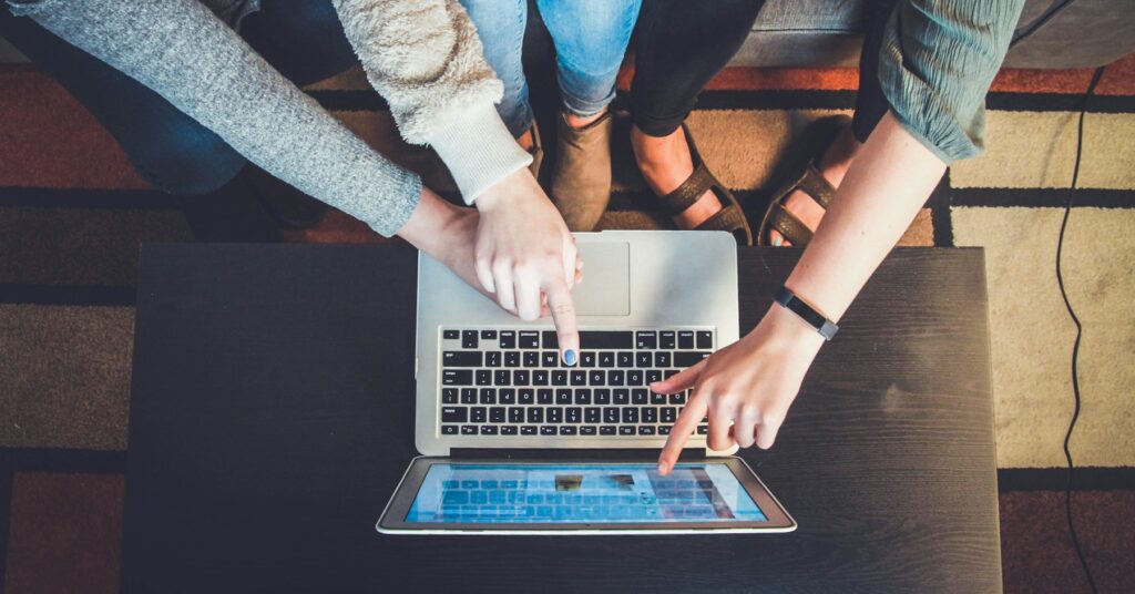 three person pointing the silver laptop computer