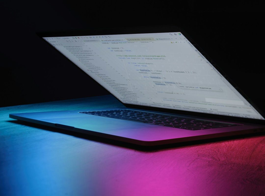 Open laptop with code on screen, neon lighting